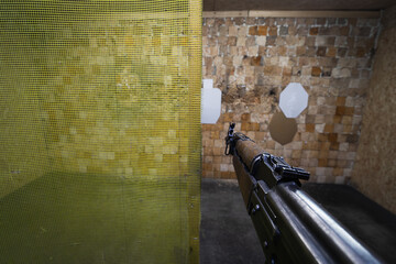 Shooting at a indoors shooting range with an old AK 47 assault rifle, first person view.