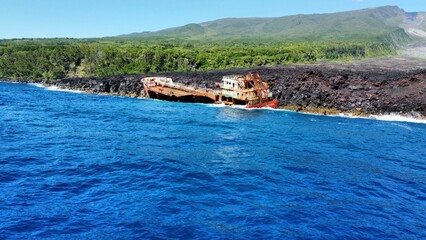 Dramatic drone photo at a abandoned shipwreck on a rough lava coastline on the island Reunion
