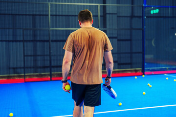 Young man prepares for a match in indoor padel court, showcasing focused energy and determination