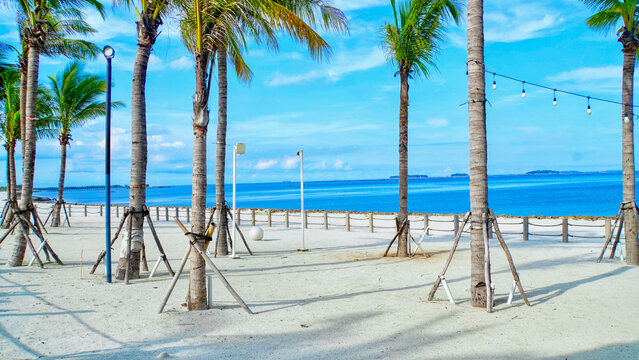 Beautiful landscape of the white sand beach or pantai pasir putih at PIK 2 in Jakarta, Indonesia. Coconut trees, white sand, blue sea, and blue sky