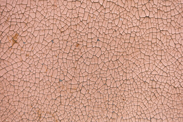 Close-up. A missing patch of stucco and paint on the wall exposing the cement brown coat, rest is cracked and peeling. Badly fixed building facade wall covered with cracks in stucco and paint