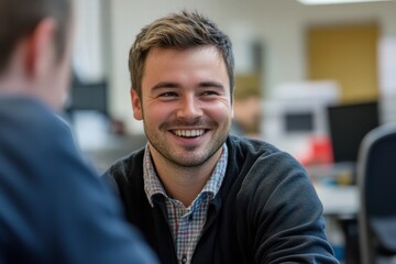 Fototapeta premium A man smiling and enjoying a friendly conversation with a colleague at work, in a comfortable office setting.