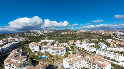 Naklejka premium Aerial drone photo of the beautiful town of Sitio de Calahonda taken in the winter time showing residential and holiday homes with swimming pools from above and the mountains in the background