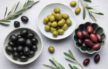 Black, green and kalamata olives displayed on bowls with olive branches