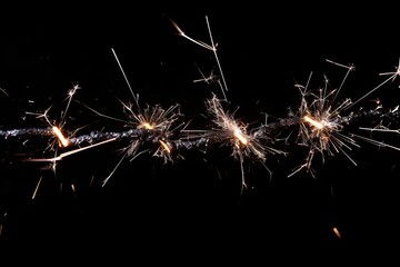 Glowing sparklers against dark background with vibrant sparks
