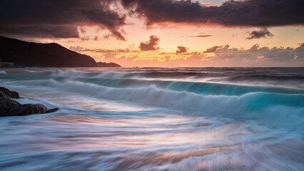Dramatic winter storm waves crash against rocky coastline with turquoise water under a vibrant sunset sky in the Far East landscape.