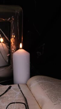 candela accesa si riflette sullo specchio rotto, libro e occhiali con ragnatele