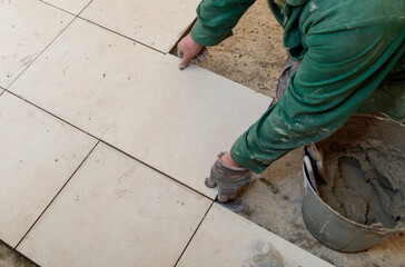A man is laying tiles on a floor