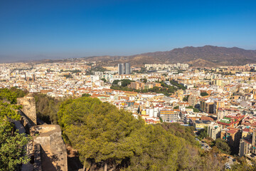 Fototapeta premium Malaga, seaside city in Andalusia, Spain, Europe. Panoramic view of a city nestled in a valley, surrounded by mountains under a clear blue sky.