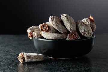 Dried persimmons in a black dish.
