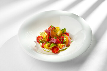 A vibrant and refreshing summer salad featuring ripe tomatoes, creamy avocado, and sweet peaches. The salad is tossed in a light vinaigrette and served on a bed of fresh greens.