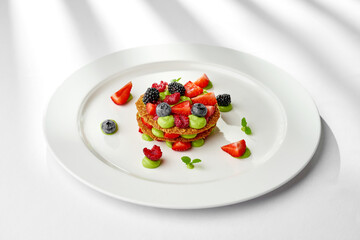 A vibrant and refreshing mille-feuille dessert, layered with fresh berries and a light cream. The dessert is garnished with a sprig of mint, creating a visually appealing and appetizing composition
