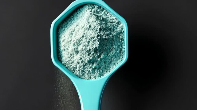 Blue spoon with a blue powder on it. The spoon is on a black background