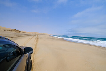 A 4x4 adventure along the wild shores of Sandwich Harbour, where vehicle tracks carve through the sand, revealing a stunning landscape where desert and ocean collide.