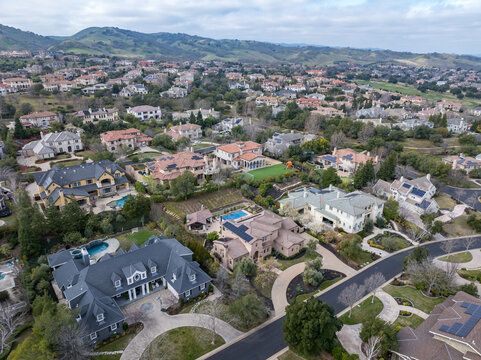 Aerial images over an affluent community in the Bay Area, with mansions, cars, solar, pools