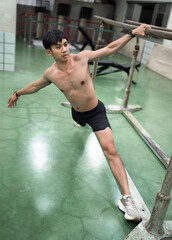 Fototapeta premium Asia young man warm up or exercising on parallel bars at gym 
