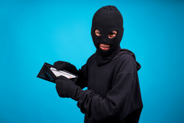 A Mugger In Mask Showing Money On Wallet Isolated on Blue Background 