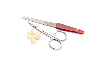 a nail scissors, file and some nail clippings over a white surface