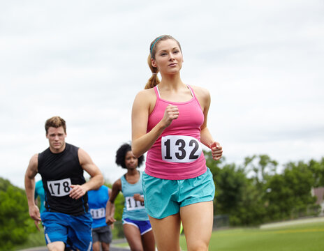 Energy, running and people at outdoor track with race, marathon or relay for charity event.Fitness, workout and group of athletes with cardio challenge, exercise or training for athletic championship