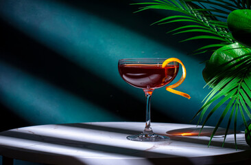 Rusty compass alcoholic cocktail drink with scotch whiskey, liqueur and orange twist. Green background, hard light and shadows