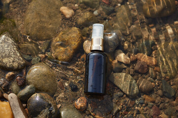 Black spray bottle on river rocks