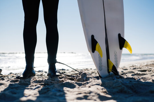 Surfer standing on the beach with surfboard ready to ride waves