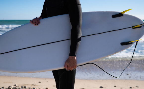 Surfer holding surfboard on sunny beach after surfing session