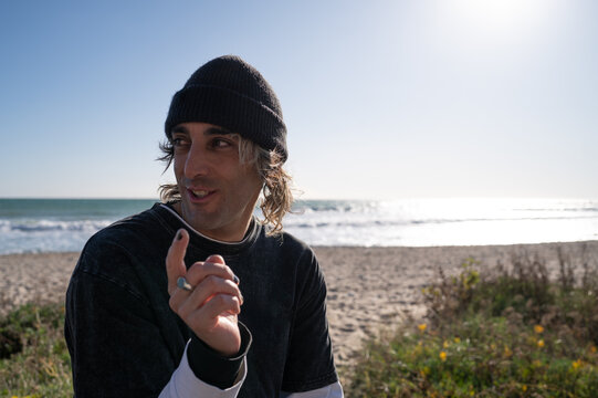 Surfer pointing finger with ocean in background on sunny day