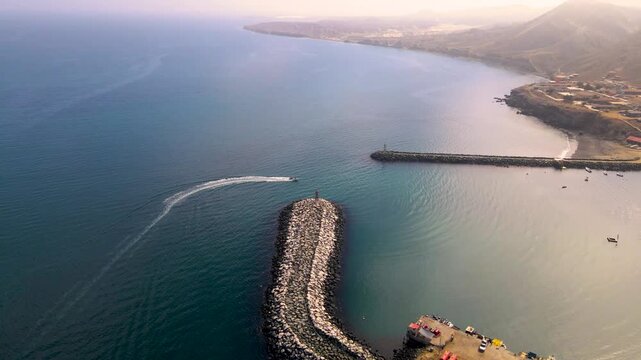 Aerial high angle overview of Cedros Island dock surrounded by turquoise waters, showcasing fishing activity below as boat enters harbor