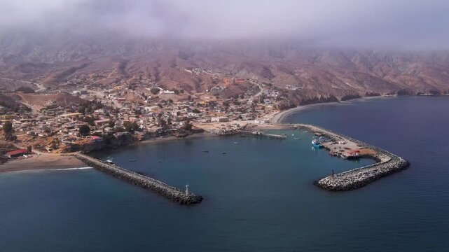 Aerial establishing frontal overview of Cedros Island&rsquo;s fishing harbor, turquoise waters, and docked fishing boats