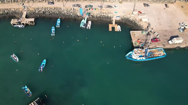 Aerial pullback tilt up along Cedros Island docks and fishing boats, showcasing local marine activity and scenic views
