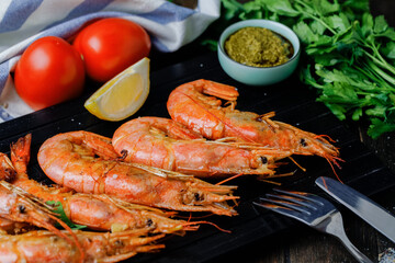 Roasted langoustines with spices and garlic on black board background. Close up. View above.