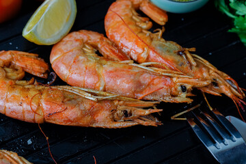 Roasted langoustines with spices and garlic on black board background. Close up. View above.