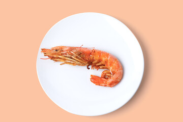 Close up of Red cooked shrimp on white plate isolated on a light salmon color background. Copy space.