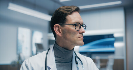 Obraz premium Portrait of a Male Physician in a Hospital Office, Wearing Glasses and a Stethoscope, Looking to the Side. Medical Help and Healthcare Solution, in Modern Clinical Setting