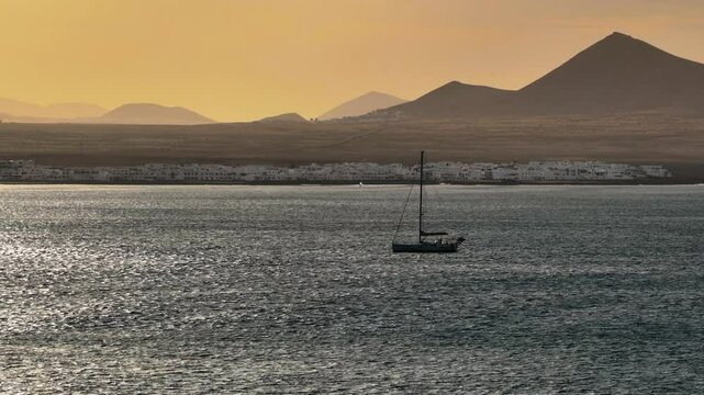 Voilier sur l'oc&eacute;an Atlantique &agrave; Famara - Lanzarote pendant le coucher de soleil avec les volcans en arri&egrave;re plan
