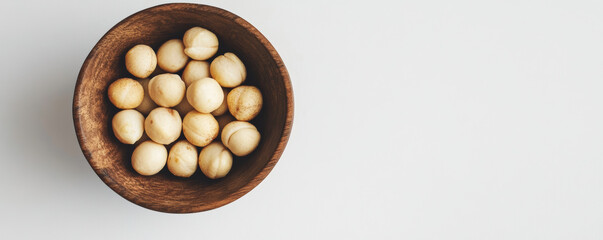 Artistic flat lay of macadamia nuts in natural wooden bowl, showcasing their creamy texture and unique shape. Perfect for healthy snacking or culinary use