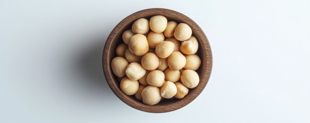 Close up view of macadamia nuts in wooden bowl, showcasing their smooth texture and creamy color. Perfect for healthy snacking or culinary use