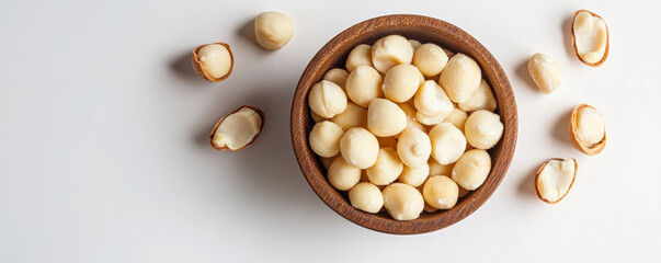 wooden bowl filled with macadamia nuts, surrounded by shells, showcasing their creamy texture and natural color. Perfect for healthy snacking or culinary use