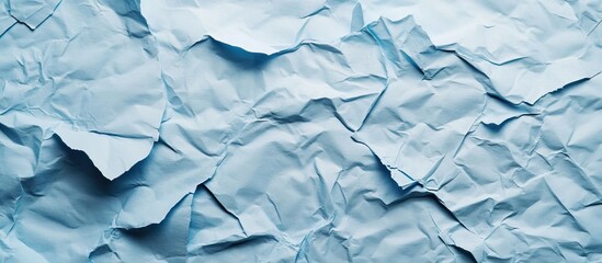 Obraz premium Crumpled light blue paper texture wallpaper with irregular folds and subtle shadows ideal for creative backgrounds and design projects
