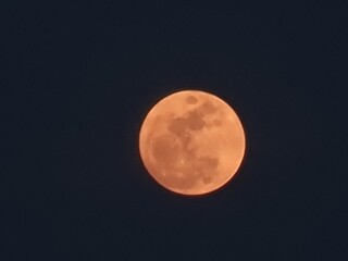Orange full moon against a dark sky background