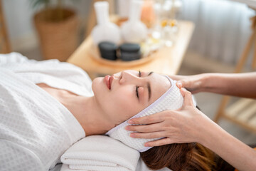 Asian young woman getting head and facial massage treatment at beauty spa. 