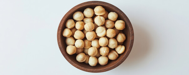 Natural wooden bowl filled with whole macadamia nuts, showcasing their creamy texture and rich color. Perfect for healthy snacking or culinary use