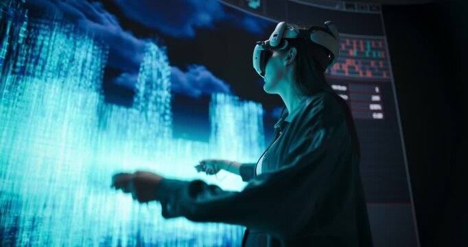 Young Woman in VR Headset Crafts Digital Cityscapes on a Large Screen, Using Innovative Virtual Reality Design Software and Futuristic Urban Planning. Architecture, Technology and Creativity Concept