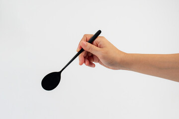 Hand and metal black spoon on white background