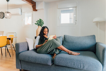 Fototapeta premium Woman relaxing on sofa reading a book in modern apartment