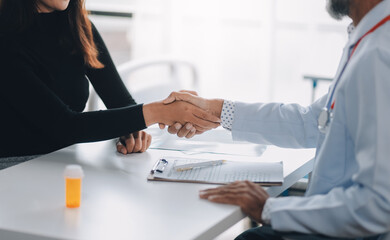 Mature doctor shaking hands with patient at clinic