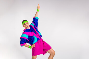 Energetic young man enjoying a funky workout in colorful retro sportswear against a white and grey...