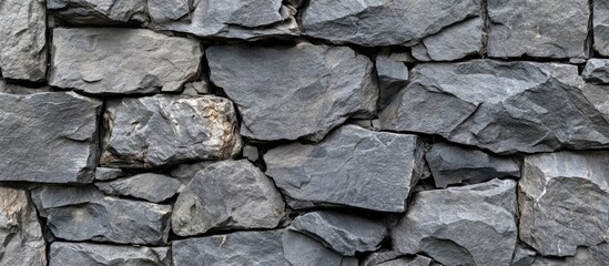 Fototapeta premium Gray textured stone wall with varying shapes and sizes of stones, arranged closely together, creating a natural rugged appearance.