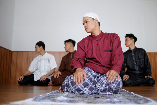 Group Of Young Muslim Friends Done Praying Salah In The Sitting Position On Last Procedure Perform Taslim. Taslim Represents The End Of Prayer.